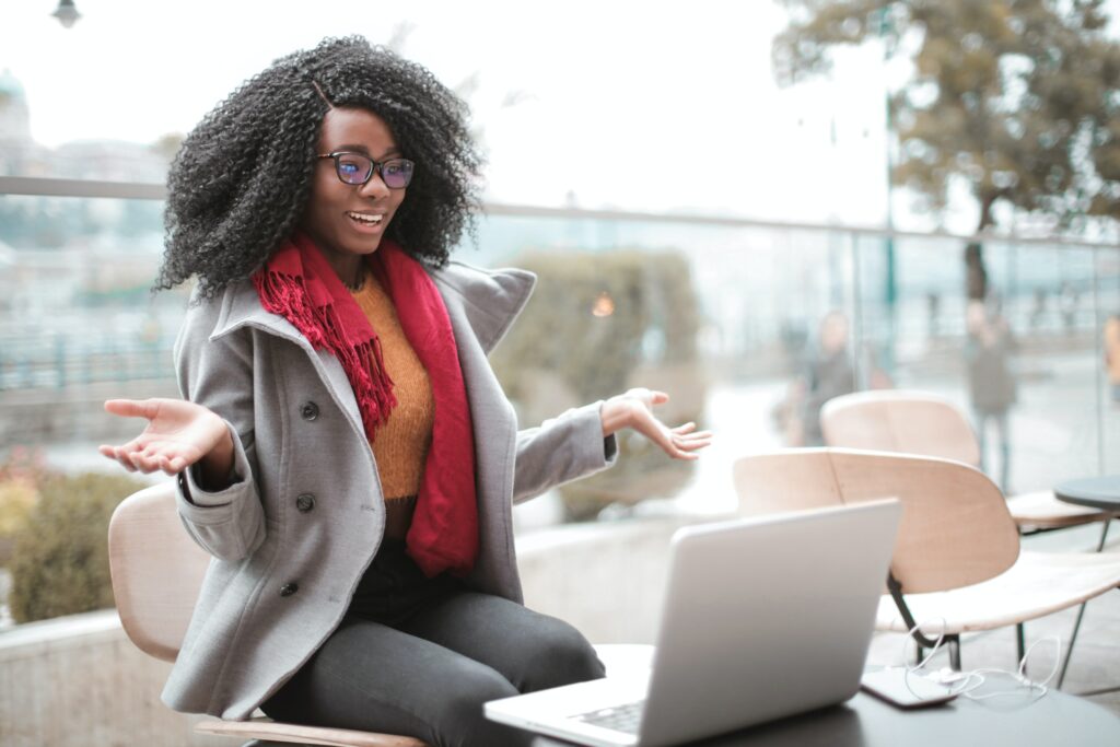 Screenshot showing a happy woman seated in front of a white laptop